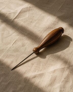 walnut bobbin lace pricker handle on raw linen with cinematic soft light and clean negative space for premium stock background