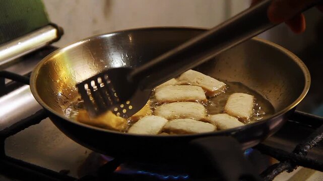 Slices of fresh tofu being fried in a frying pan.