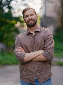 Smiling handsome bearded man with arms crossed standing on city street