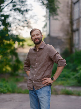 Smiling handsome bearded man standing with hands on hips on city street