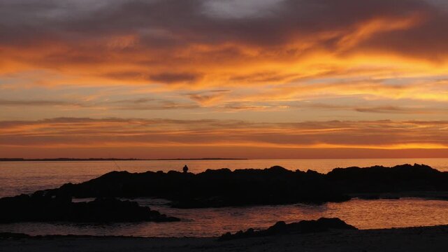 4K 25fps sunset footage from Bloubergstrand showing the rugged rocky coastline and distant Robben Island across Table Bay, bathed in warm golden light along Cape Town&rsquo;s Atlantic shoreline.