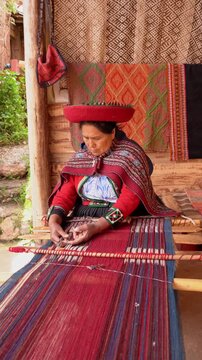 Peruvian woman in traditional clothing weaving a colorful textile using a handmade loom in cuzco