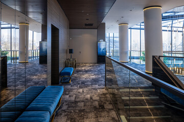 Naklejka premium Elegant hotel hallway interior with blue velvet benches and glass railings