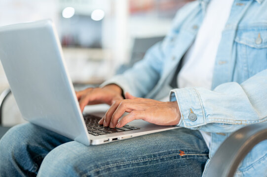 Close up of a man's hands typing on laptop in cafe, representing remote work and digital lifestyle.