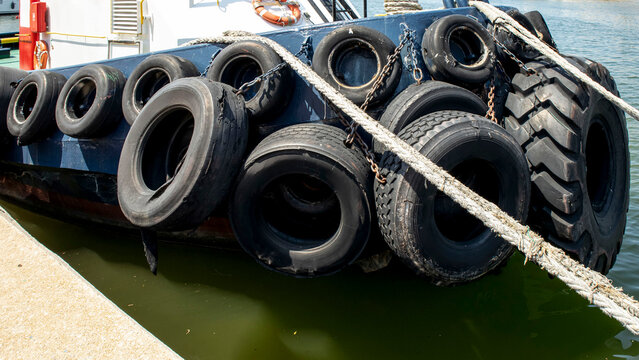 Close up view of a tugboat bow with rubber tires and chains for marine protection by the dock at the harbor