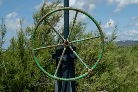 Close up of a green metal valve wheel in a rustic irrigation system used in agriculture