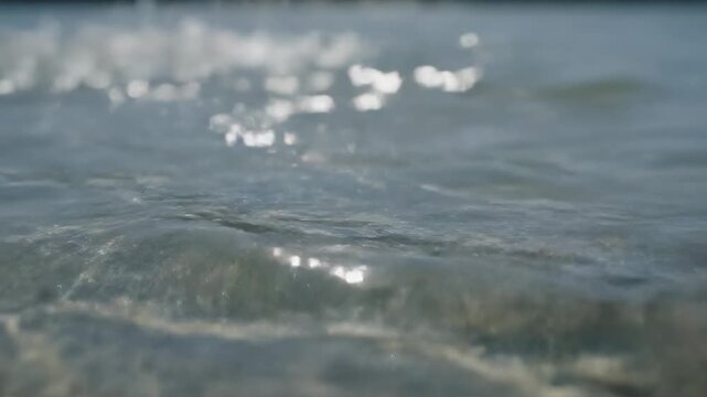 Gentle ocean waves with sun glinting on the surface during daylight