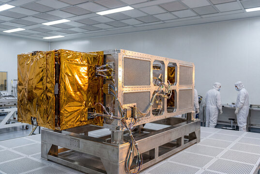 Satellite integration inside cleanroom with engineers inspecting spacecraft module