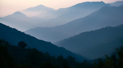 Fototapeta premium A quiet misty mountain range is bathed in gentle dawn light as soft shadows dance across the rugged peaks