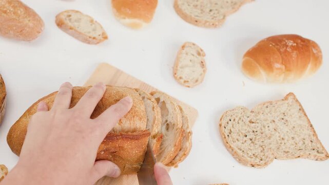 Hands Slicing Fresh Crusty Sourdough Bread on Wooden Board