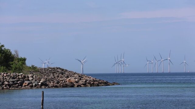 Epic motion time-lapse vid. Powerful offshore wind turbines at Lillgrund spinning under a dynamic sky. A beautiful lone seabird floats in the wind, creating a breathtaking, sustainable energy concept.