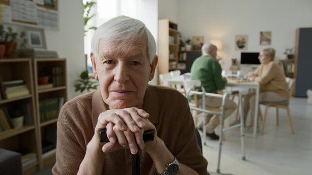 Portrait of senior man leaning on walking cane in nursing home and looking at camera. Clip senior care, retirement community marketing and geriatric healthcare ads