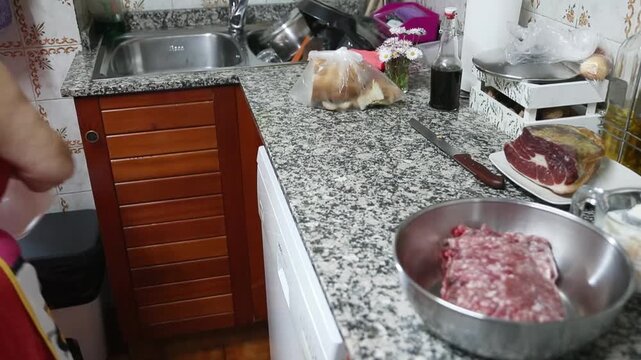  Mujer mayor agregando carne molida y ajo en un taz&oacute;n para mezclar. Abuela mayor mezclando carne molida y ajo en un taz&oacute;n. Receta tradicional de alb&oacute;ndigas caseras, aut&eacute;ntica cocina senior.