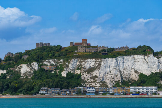 Dover castle atop white chalk cliffs overlooking a seaside town