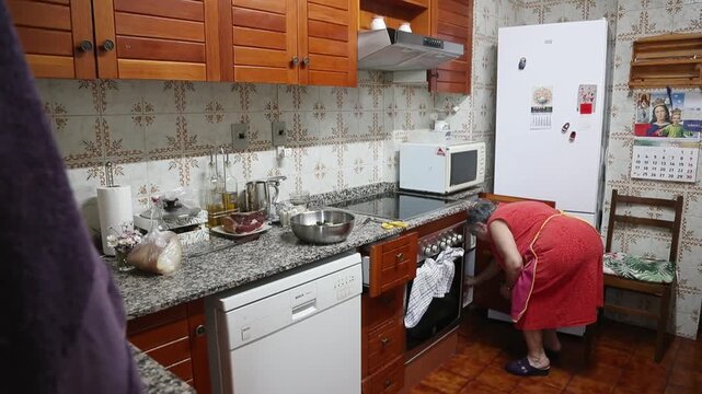  Mujer mayor agrega pan empapado en leche al taz&oacute;n para mezclar alb&oacute;ndigas. Abuela mayor agrega pan empapado en leche al taz&oacute;n. Receta tradicional de alb&oacute;ndigas caseras, aut&eacute;ntica cocina senior.