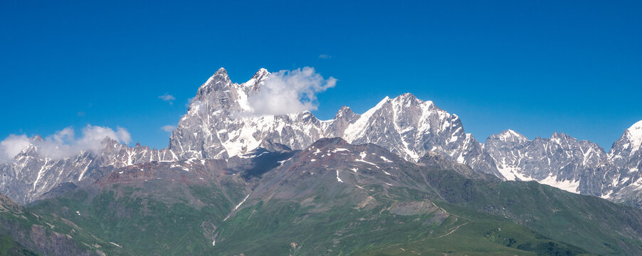 Georgia Caucasus panoramic snow capped mountain range under blue sky, alpine landscape, adventure travel, hiking destination.