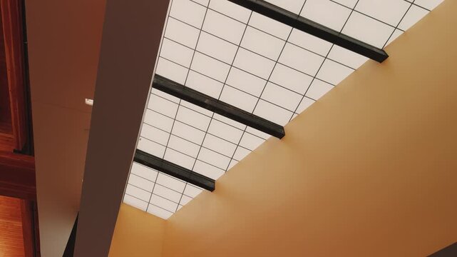 Slow downward pan across geometric skylight panels and architectural interior details with warm lighting.