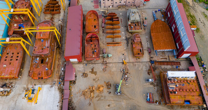 Top down aerial drone shot of rusty ship hulls undergoing extensive repairs at an industrial dry dock