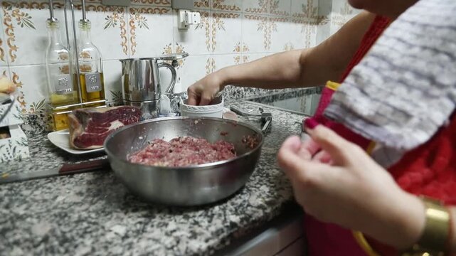  Mujer mayor mezclando ingredientes de alb&oacute;ndigas a mano en un taz&oacute;n. Abuela mayor amasando y mezclando ingredientes de alb&oacute;ndigas a mano en un taz&oacute;n. Cocina tradicional casera, aut&eacute;ntica senior.
