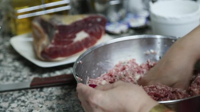  Mujer mayor mezclando ingredientes de alb&oacute;ndigas a mano en un taz&oacute;n. Abuela mayor amasando y mezclando ingredientes de alb&oacute;ndigas a mano en un taz&oacute;n. Cocina tradicional casera, aut&eacute;ntica senior.