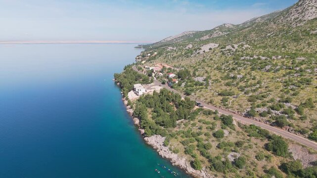 Drone over the Adriatic Highway between Starigrad and Karlobag, showing the thin coastal road, Adriatic Sea, scattered houses, and a backward reveal of the Velebit mountain range.
Croatia,
