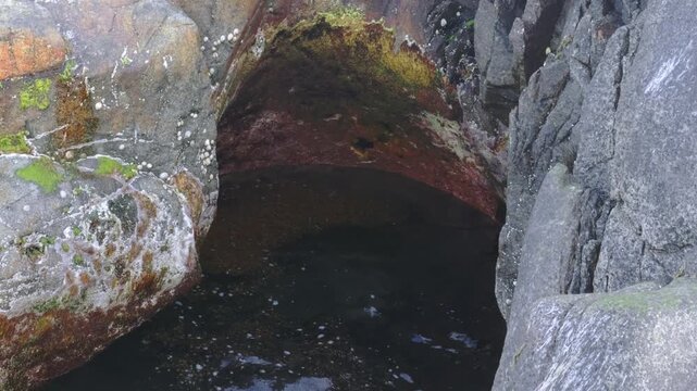 View of a coastal rock hollowed by seawater, where waves and tides have carved a nearly spherical, meter-wide basin. Lofoten Islands, Northern Norway.