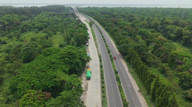Highway Road Through Dense Forest with Moving Vehicles and Aerial Perspective Showing Traffic Flow and Commuting
