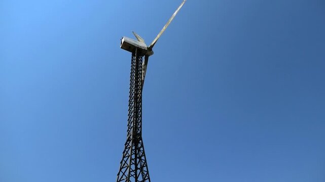 Closeup of a working windmill turbine in the background of blue sky