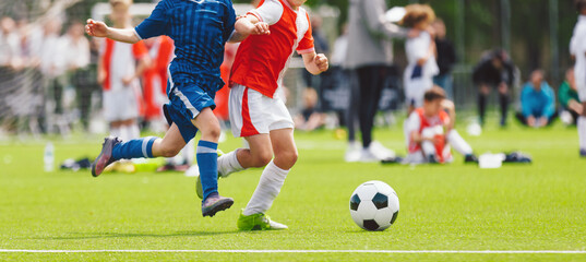 Obraz premium Children Football Match: Action View of Young Players in Red and Blue Uniforms on Field