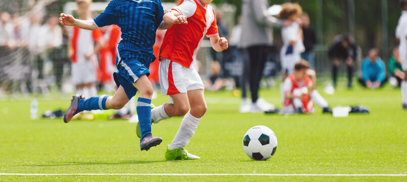 Children Football Match: Action View of Young Players in Red and Blue Uniforms on Field