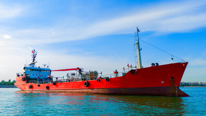 Side profile aerial perspective of an anchored bright orange tanker ship contrasting against the ocean © Buğra Kaan Ersoy