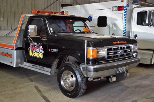 Black Ford flatbed tow truck parked inside garage