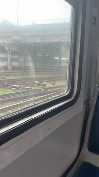 Train window view of railway tracks and urban industrial landscape, commute, transportation, travel, motion, railway infrastructure.