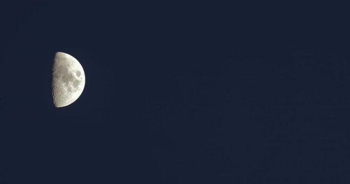 A crescent Moon illuminates the deep blue sky, revealing intricate craters and textures on its surface. The serene scene captures the beauty of our Earth's natural satellite. The waxing moon