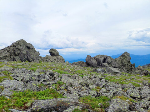 Mountain landscape with green grass, rocks and blue sky with clouds