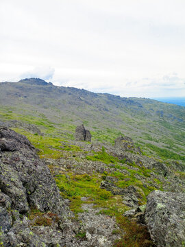 rocky mountain top in summer with green slopes and cloudy sky