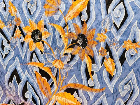 A beautiful Indonesian batik fabric featuring floral, leaf, and cloud motifs from the city of Cirebon, dominated by blue and brown hues.