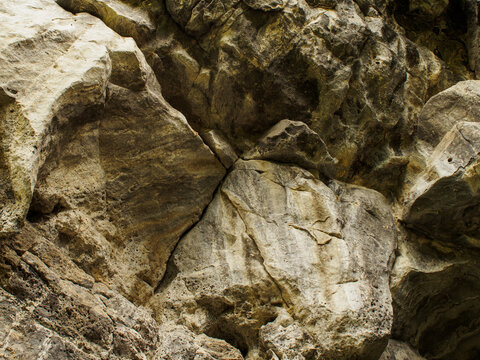 Horizontal photo of a close up solid rock wall background with detailed geological texture, sharp natural mountain stone surface with cracks and rough pattern, scenic organic gray mineral backdrop