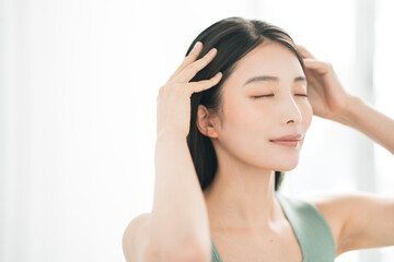 Naklejka premium 目を閉じ頭皮や髪をケアするアジア人女性のウェルネスポートレート