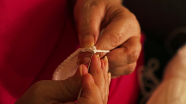 Woman's hands crocheting white yarn piece with hook close up. Handmade crafts, hobbies, slow living, and textile arts concepts.