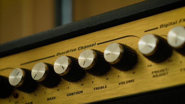 Rotary control knobs for volume, tone, and effects adjustment. Macro view of metallic dials on audio equipment control panel. User interface design, sound customization, and precision settings concept
