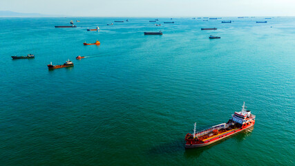 Wide aerial shot of a red and black tanker with dozens of ships anchored in the distance © Buğra Kaan Ersoy