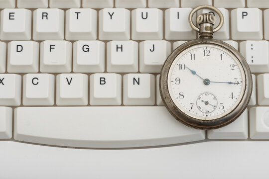 vAntique pocket watch on a white computer keyboard for deadlines
