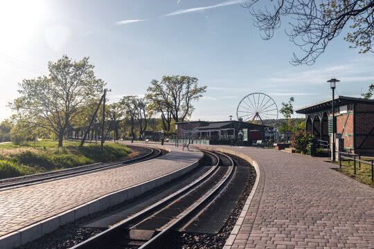 View of the narrow-gauge railway station platform and train tracks with a Ferris wheel visible in the background in Sellin, Ruegen island, Germany.