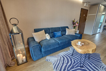 Salon w nowoczesnym apartamencie z niebieską kanapą  i drewnianym stolikiem kawowym © arteffect.pl