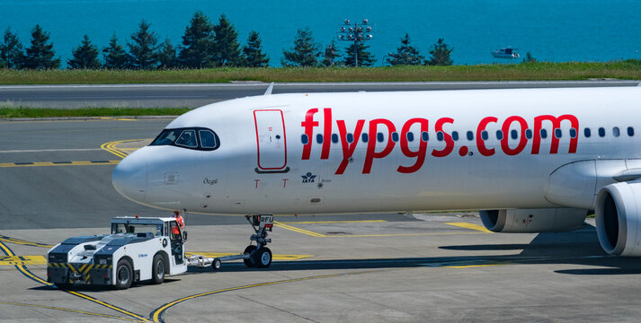 Profile View Of A Pegasus Airlines Commercial Passenger Aircraft Nose Section Being Assisted By A Specialized Pushback Tractor Vehicle On The Concrete Airport Tarmac