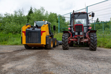 Obraz premium Red tractor and yellow skid steer loader parked outdoors