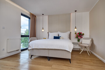 Sypialnia w nowoczesnym apartamencie z dużym  łóżkiem, fotelami, kwiatami i beżową szafą © arteffect.pl