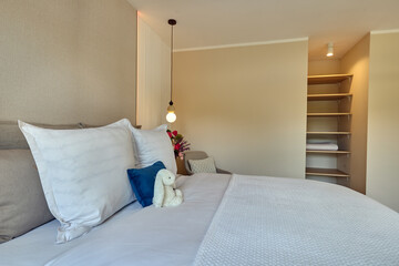 Sypialnia w nowoczesnym apartamencie z dużym  łóżkiem, fotelami, kwiatami i beżową szafą © arteffect.pl
