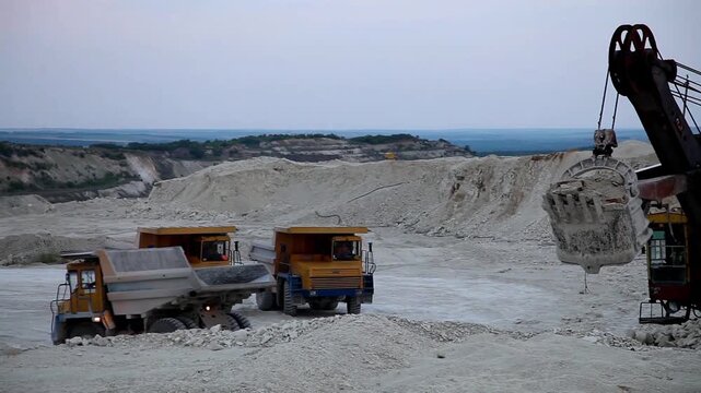 Huge mining dump truck moving stones in an open-pit quarry against a blue sky background